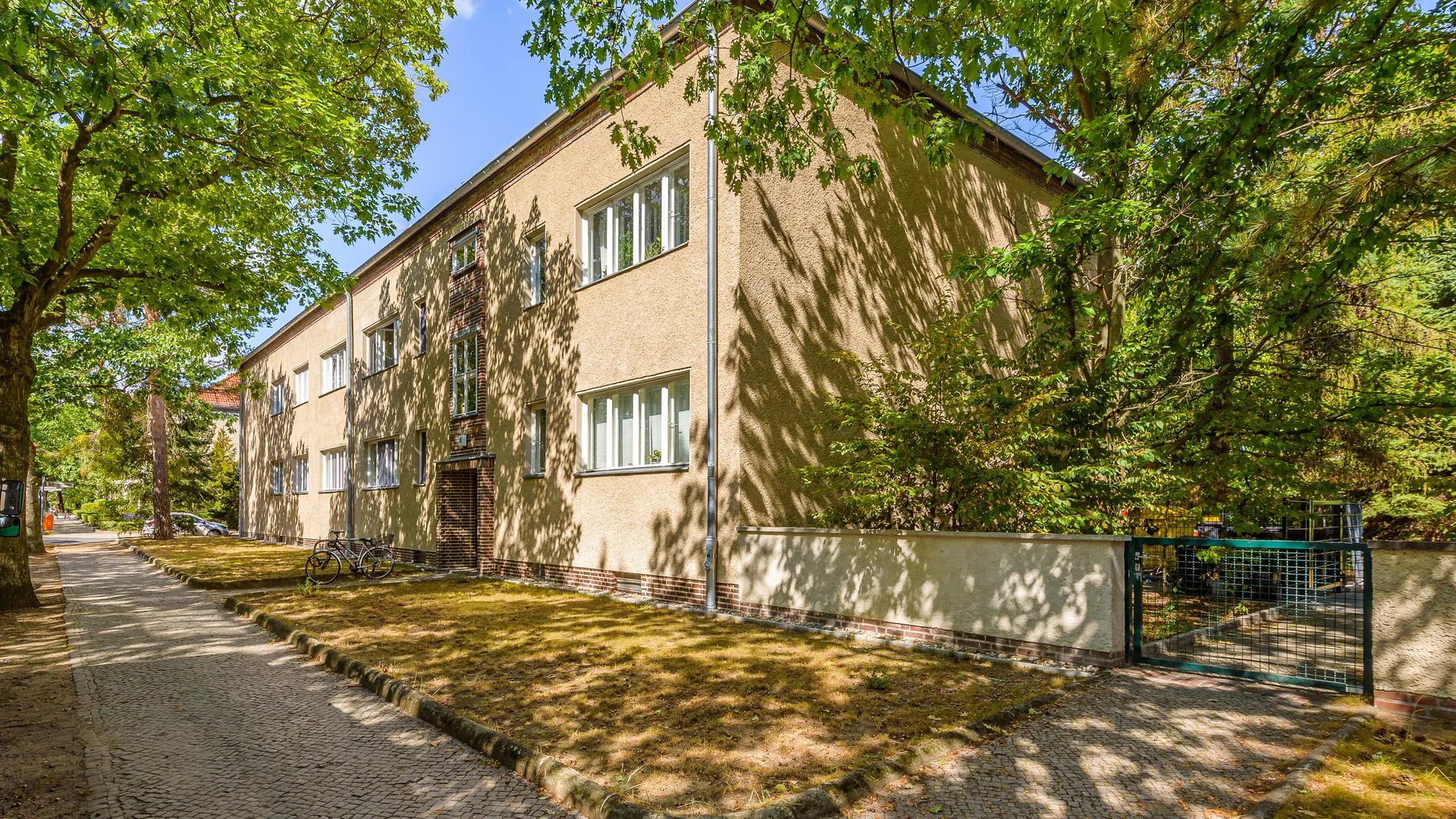 Denkmalgeschütztes Wohnhaus mit Backsteinfassade an einer Baumallee in Berlin-Köpenick