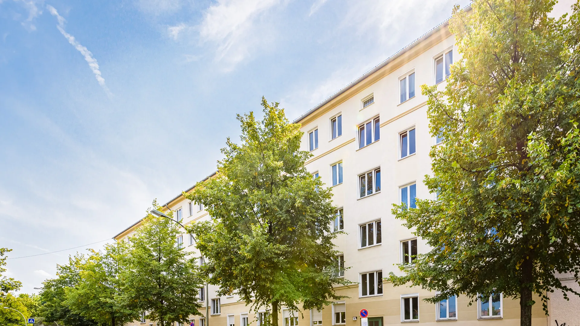 Hellgelbes Mehrfamilienhaus an einer Straße mit Linden in Berlin-Friedrichshain